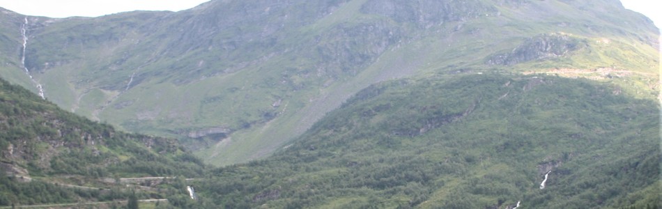 Foto av nedskåret dallandskap med bart fjell over skoggrensen med innsjø