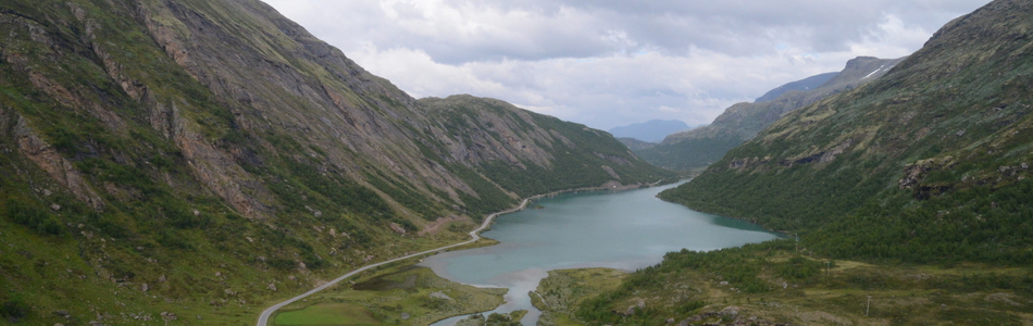 Foto av nedskåret dallandskap med hei under skoggrensen med innsjø og bebygde områder