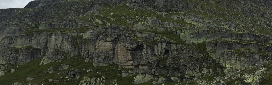 Foto av tindepreget ås- og fjellandskap med hei over skoggrensen